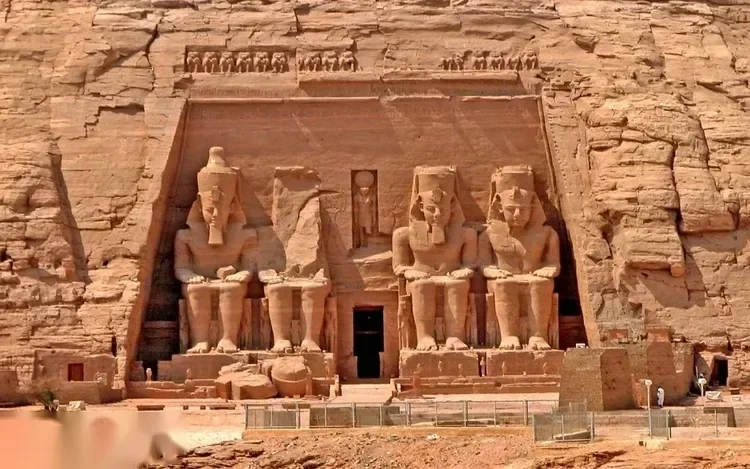 Close-up of the four colossal seated statues of Ramses II on the sandstone facade of the Great Temple.