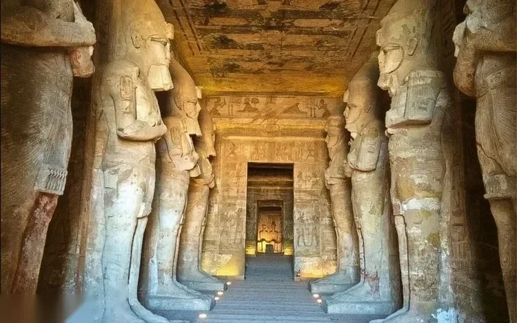 An illuminated interior hall of the Great Temple lined with tall statue-pillars leading to the inner sanctuary.