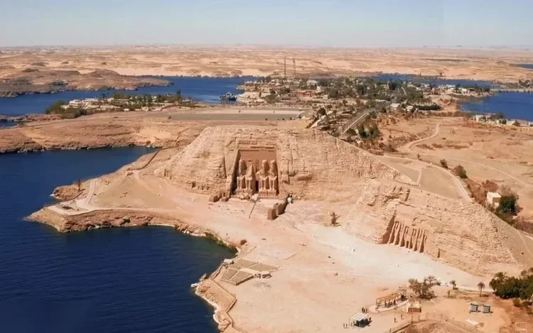 Wide aerial view of the Abu Simbel temple complex and surrounding village beside Lake Nasser.