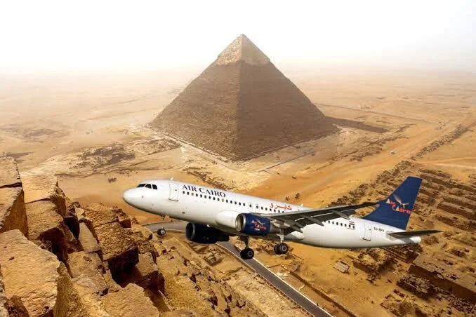 A digitally composited image showing an Air Cairo passenger jet flying dramatically close above the Great Pyramid.