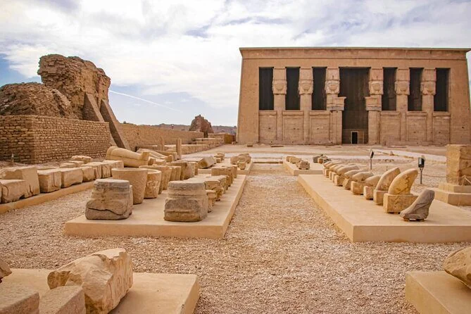 Stone pathway leads to the imposing facade of Dendera Temple with rows of Hathor-headed columns.