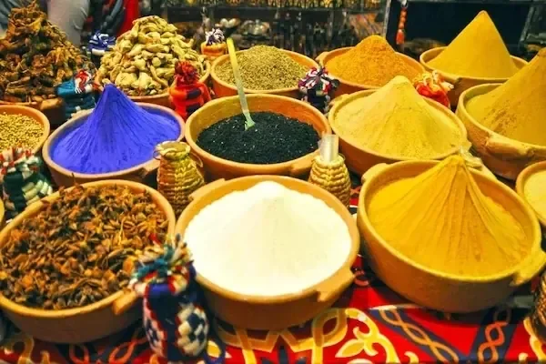 Close-up of various spice bowls and small bundled souvenirs arranged on a market table.