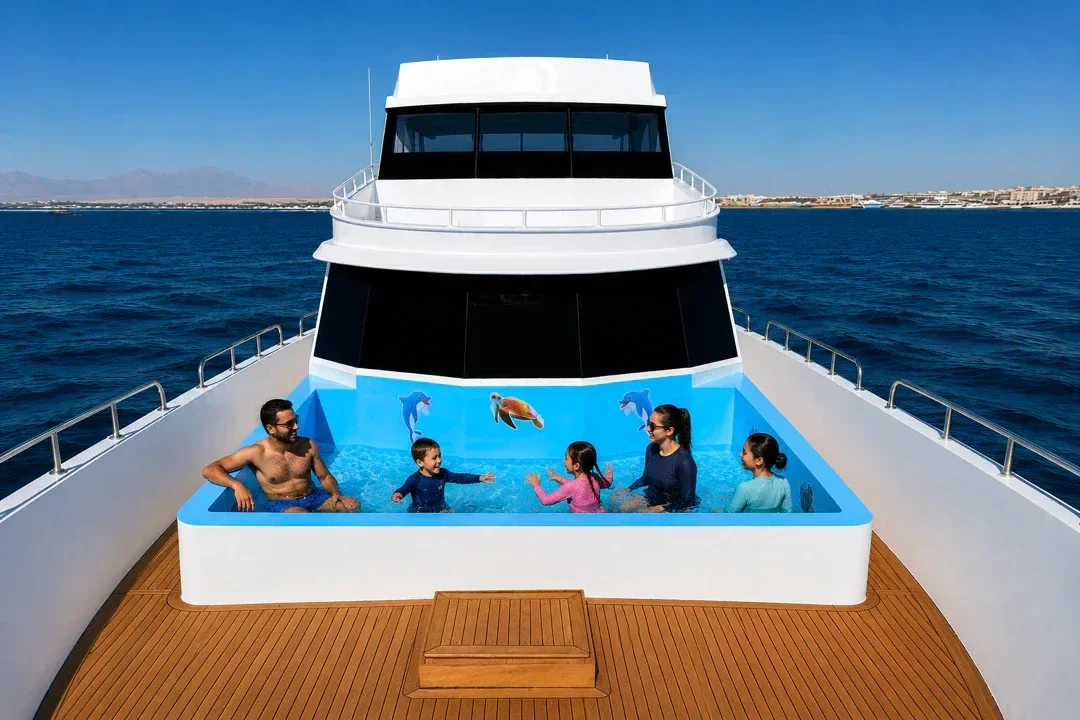 A family swimming together in the yacht's onboard pool, decorated with dolphin and turtle graphics, with the coastline behind.