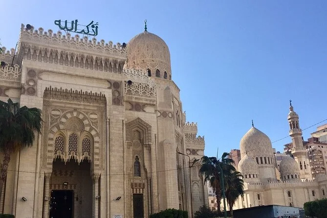 Low-angle view of the ornate stone facade, dome and minaret of the Abu al-Abbas al-Mursi Mosque against a clear blue sky