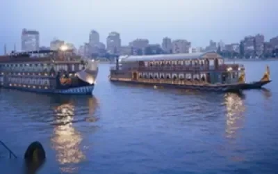 Diners sit at candlelit tables inside a restaurant or cruise boat in the evening.