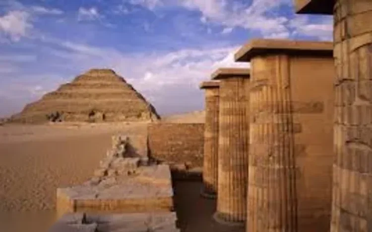 View of the Step Pyramid of Djoser across the desert, framed by a row of stone columns in the foreground.